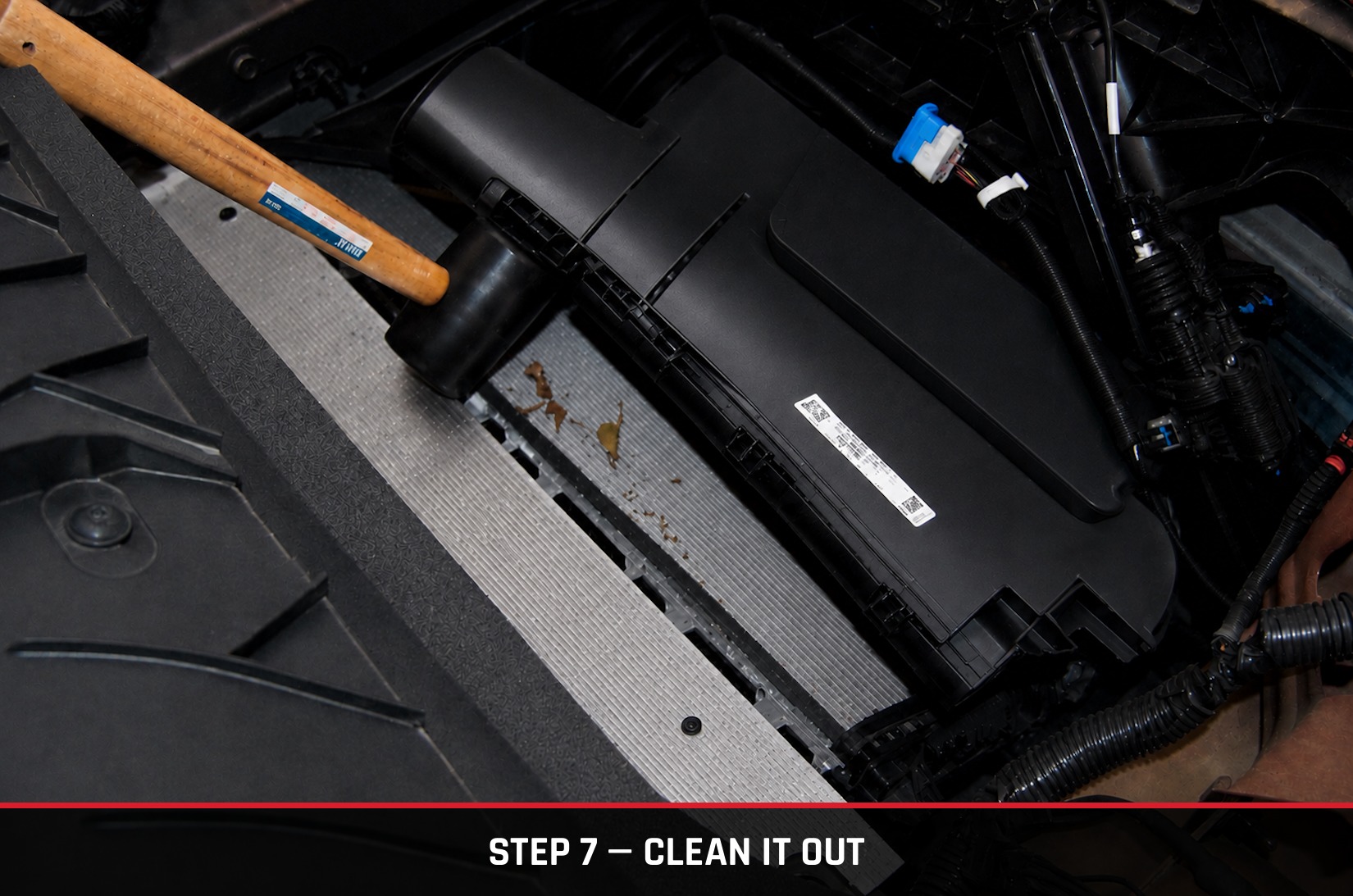 Radiator fins exposed with debris, being cleaned with a shop vac