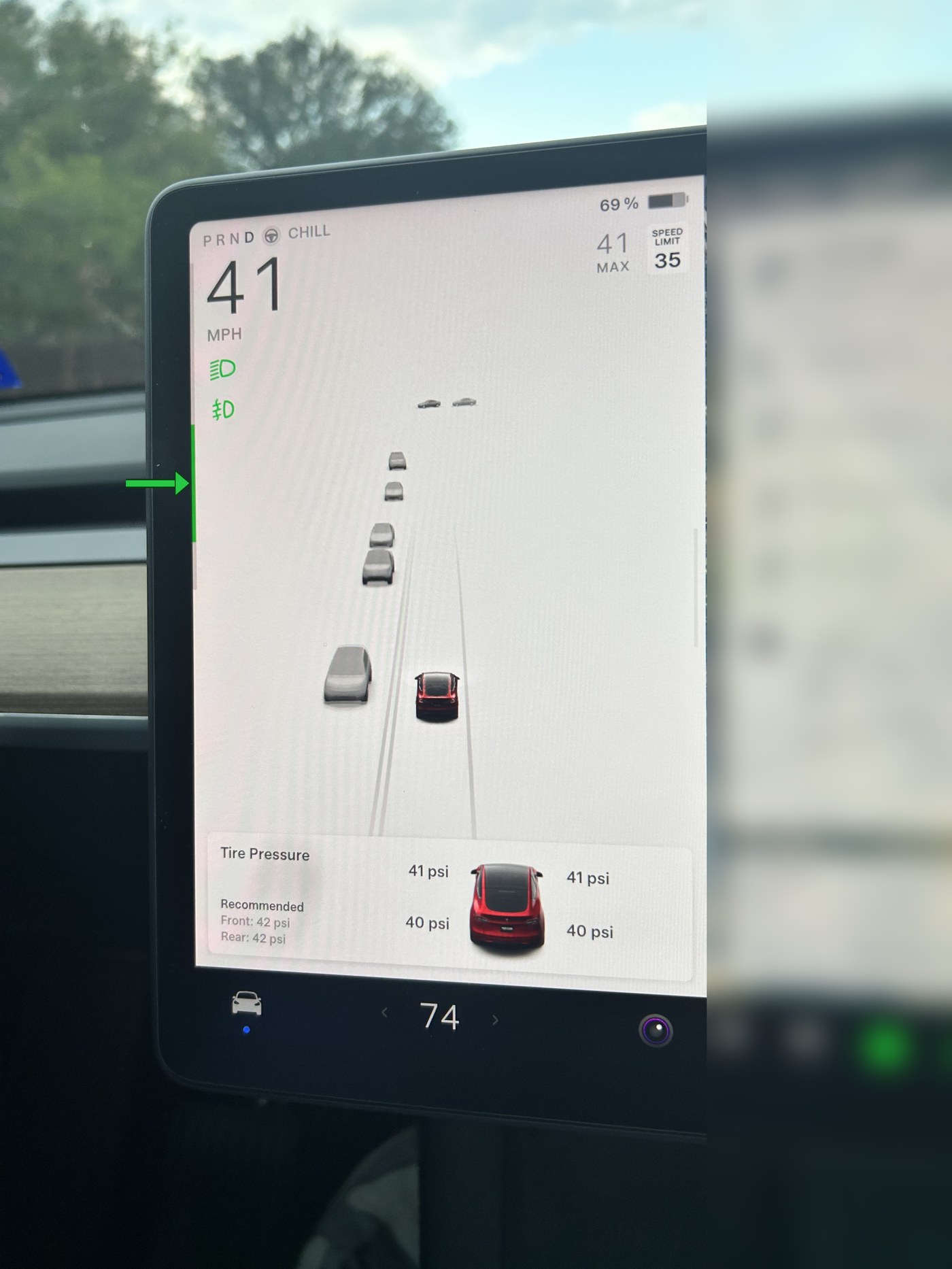 Tesla Model Y touchscreen with a green arrow pointing to the regenerative braking indicator bar on the left edge of the display
