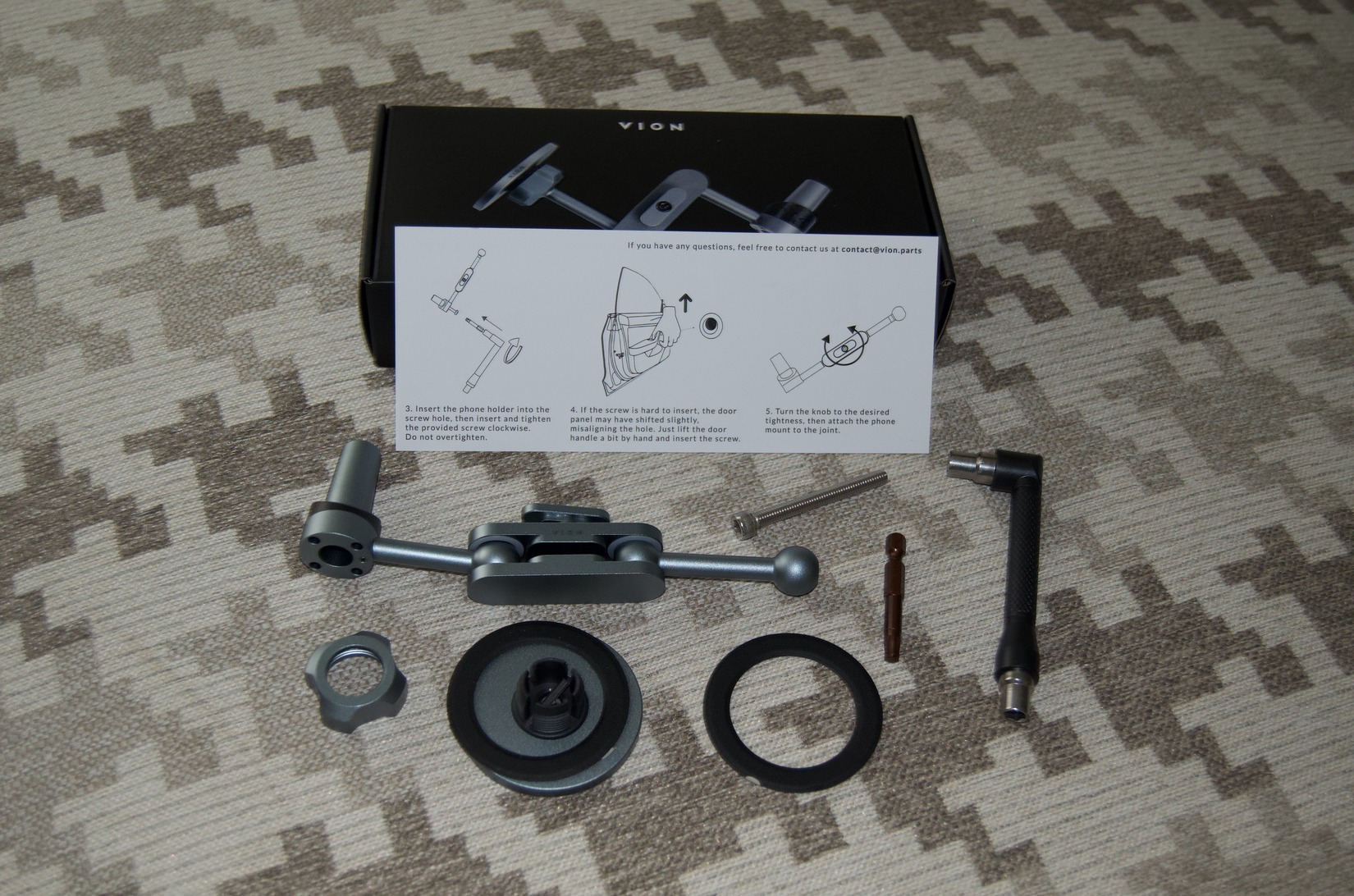 All included parts laid out: mount arm, magnetic plate, hardware, and T20 adapter with instructions
